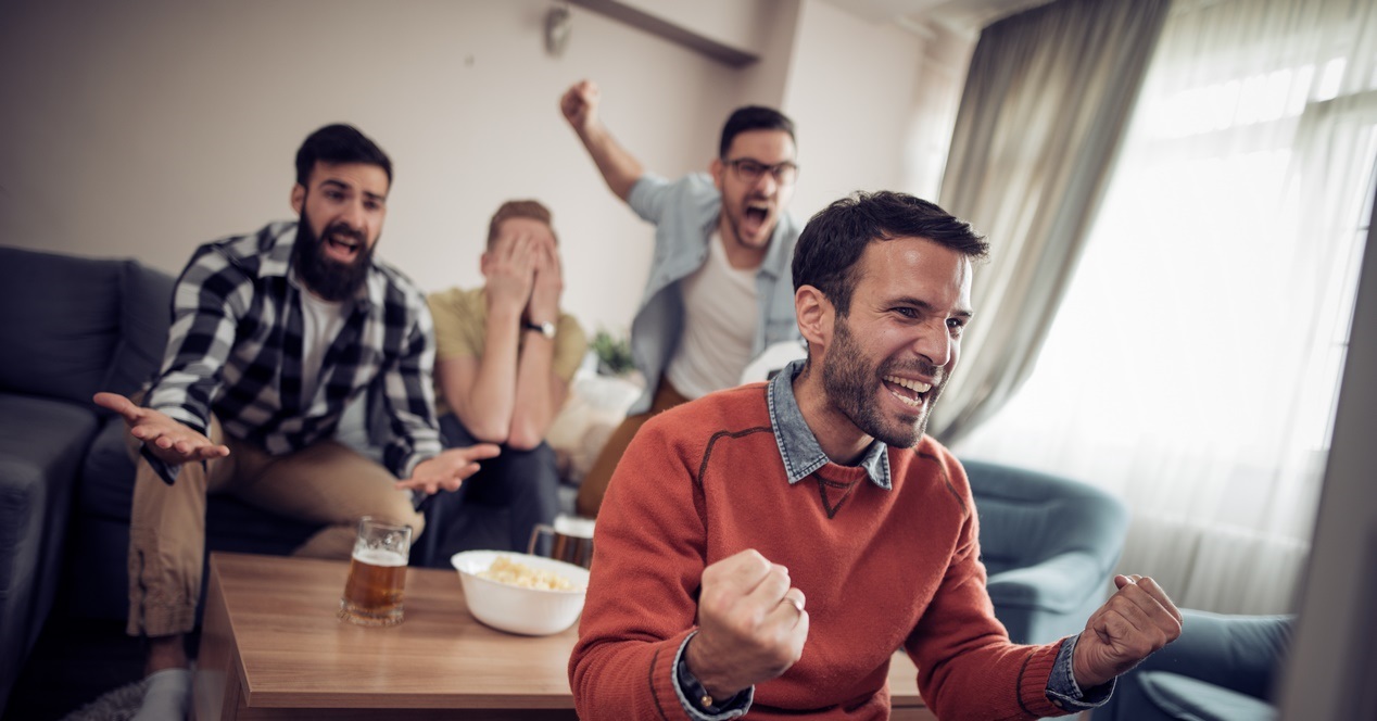 Cheerful Group Of Friends Watching Football Game On Tv
